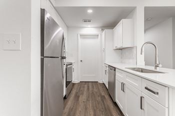 A row of urinals in a bathroom with white walls and wood floors